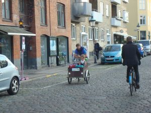 Danish guy cycling a cargo bike containing a young girl through the streets of Copenhagen. (Click to expand)
